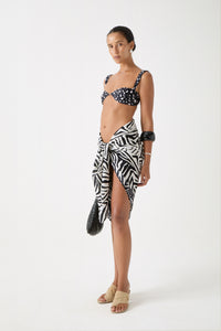 Zebra print sarong tied at waist with matte textured finish, styled with dalmatian bikini top and layered resort accessories